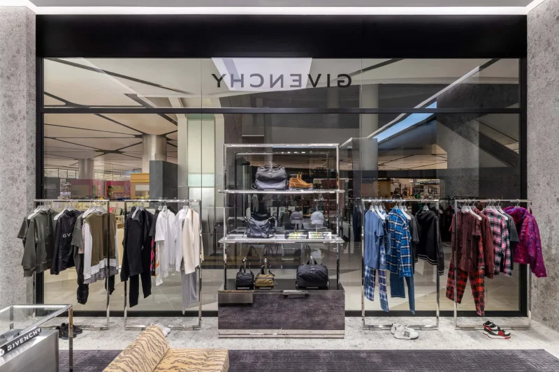 Givenchy Siam Paragon storefront window with menswear clothing racks and bag displays