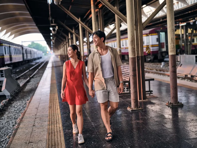Hospitality photography Thailand — couple walking hand in hand at Bangkok train station