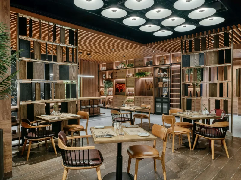 Deckles restaurant dining area at voco Surawong, with wood slat ceiling and open kitchen shelving