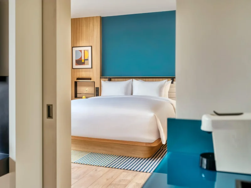 voco Surawong suite bedroom viewed through sliding door, with teal accent wall and coffee corner