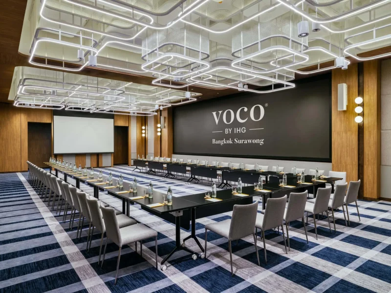 U-shape conference setup at voco Surawong ballroom with projector screen and branded wall