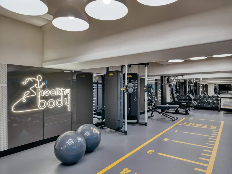 voco Surawong fitness center with Technogym equipment and neon "healthy body" sign