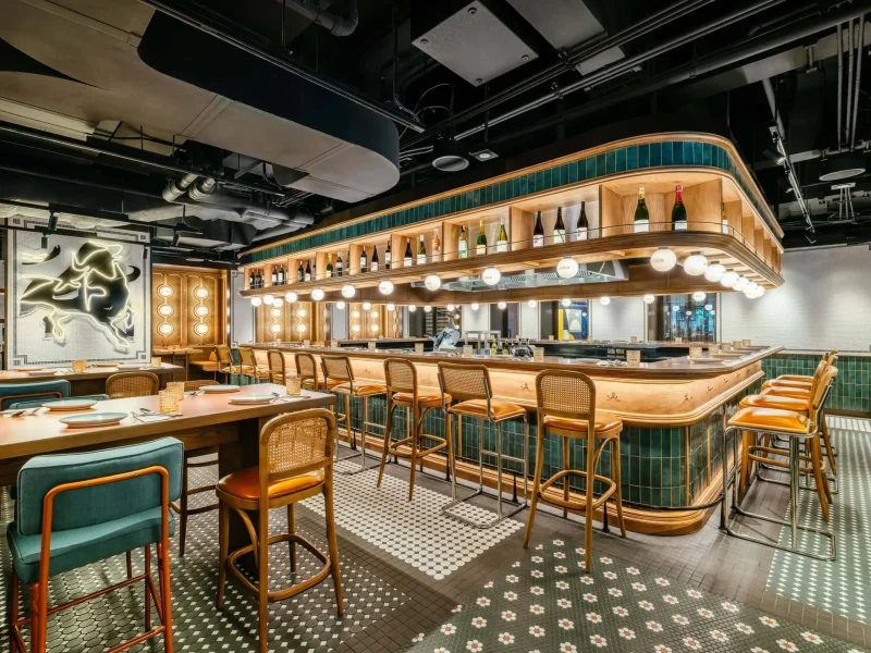 Tasca Sabio bar seating at voco Surawong, with green tile counter and neon bull art