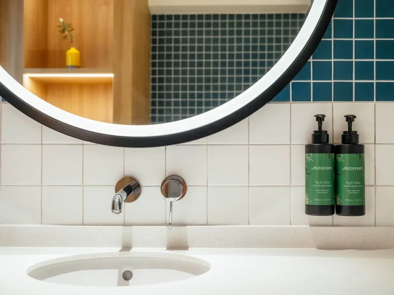 Sink detail with Antipodes amenities and round mirror in a voco Surawong bathroom