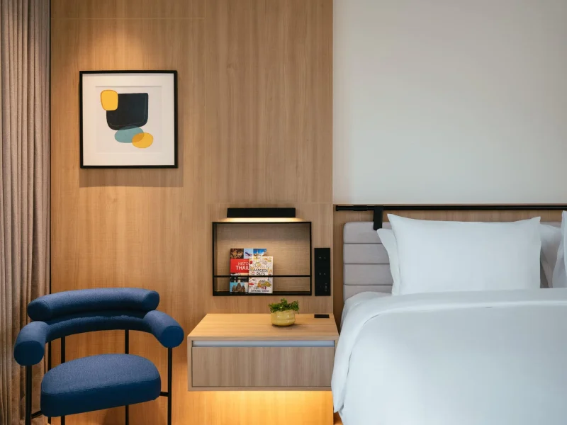 voco Surawong garden suite bedroom nightstand with abstract art and blue accent chair