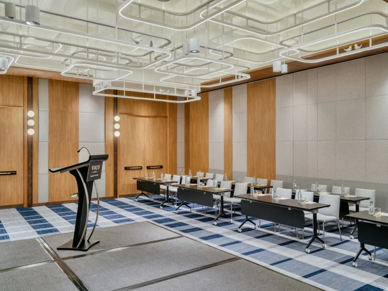 voco Surawong ballroom set classroom-style with podium and bird-motif ceiling light fixtures