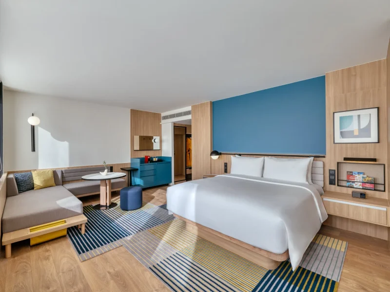 voco Surawong king grand suite with blue accent wall, lounge seating, and amenities