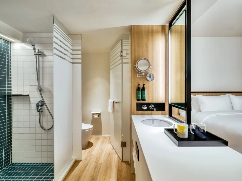Open-concept bathroom with walk-in shower and vanity opening onto the bedroom at voco Surawong