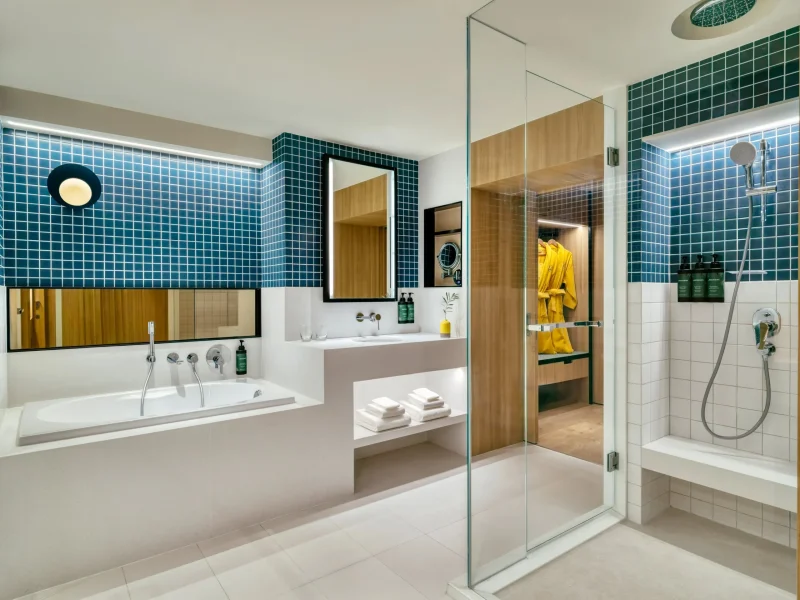 voco Surawong suite bathroom with blue mosaic tiles, soaking tub, and walk-in rain shower